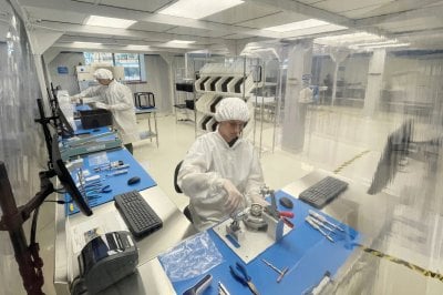 Two students wearing PPE working in a clean room.