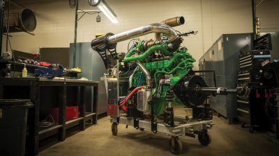 Green painted diesel engine on a cart in a lab.