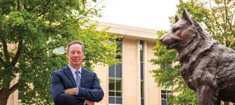 MAE Chair Jason Blough standing next to the Husky Statue.