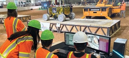 Testing PRIMROSEâ€™s excavation tools on a concrete slab. The rover is suspended by a gravity-offloading crane to simulate the moonâ€™s lower-gravity conditions.