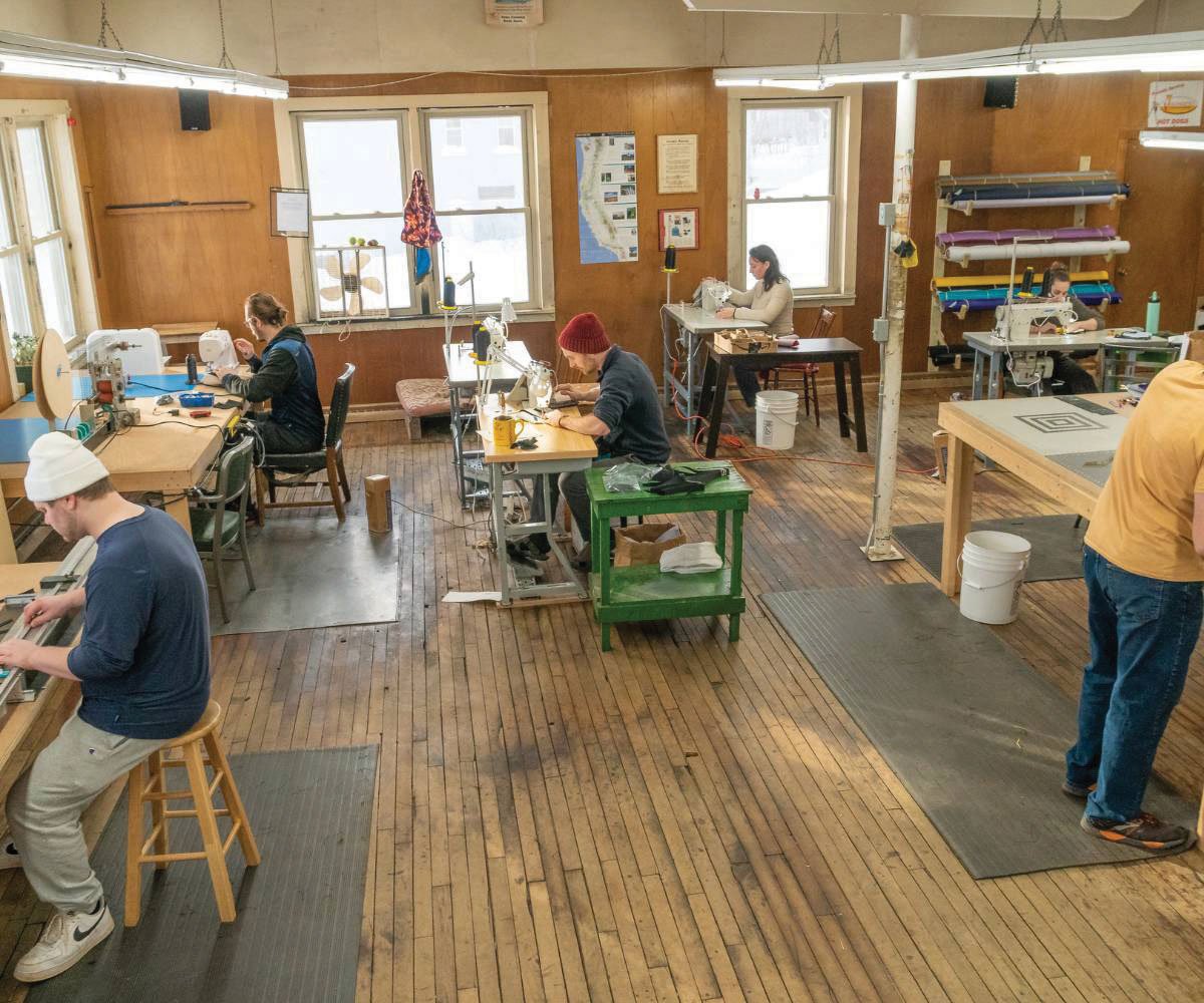 Five employees working in the shop at various equipment.