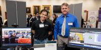 Vinh Nguyen and Alex Sergeyev standing behind their display table.