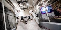 Researchers wearing personal protective equipment test a rover in the Planetary Surface Technology Development Lab's regolith sandbox.