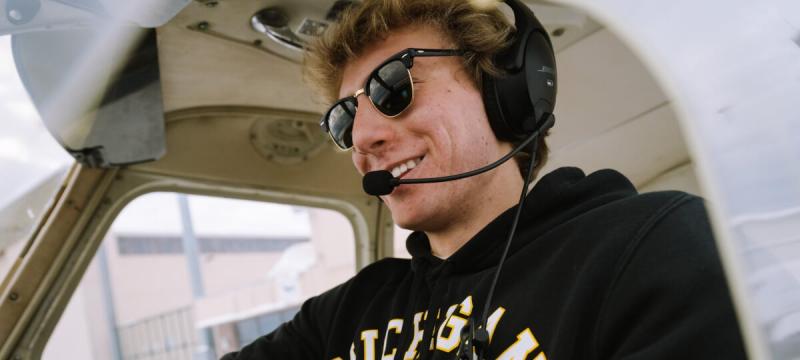 Austin Champine wearing a headset sitting in an airplane.