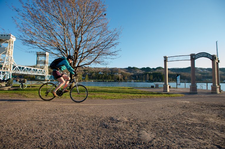 NCA Urban Person biking on the waterfront near the bridge.