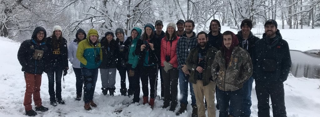 For a forestry professor, Hesterberg spent a fair bit of time in the woods — looking at birds. Today, David Flaspohler's continues the time-honored and snowy traditions of springtime birding in the Keweenaw. Credit: David Flaspohler class of students standing in snow next to a creek