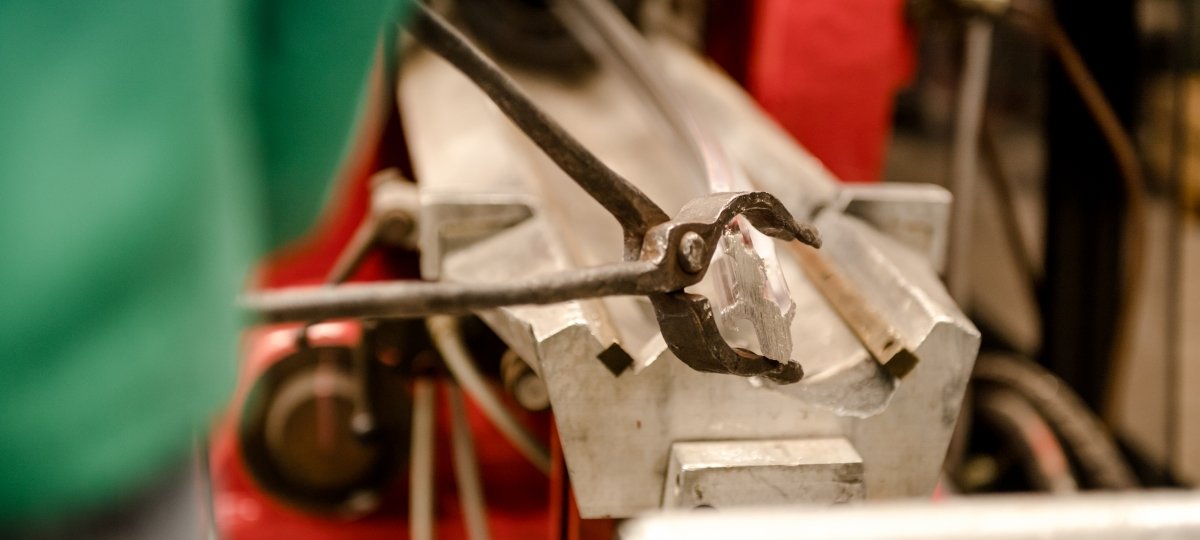 Extrusion is like a heated Play-Doh machine that squeezes out a thin rod of metal. The drawing process is similar but done at lower temperatures to make filler wire. A person uses a pair of metal tongs to pull an aluminum rod through an extruder machine.