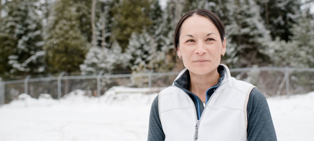 For faculty member Valoree Gagnon, director of University-Indigenous Community Partnerships, her series conversation picks up the threads of a cherished friendship with Robin Wall Kimmerer, author, plant ecologist, professor and member of the Citizen Potawatomi Nation. A woman smiles in the snow wearing a white vest with a fence, drifts, and snow-capped evergreen treeline behind her.