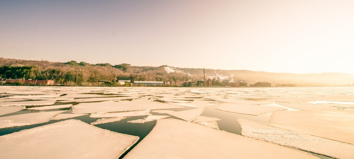 The pandemic was isolating for many, especially if they did not have the technical skills to navigate digital interactions. The Illuminated Devices project wants to help. A distant cluster of buildings is lit by bright morning sun with broken ice floes in the foreground.