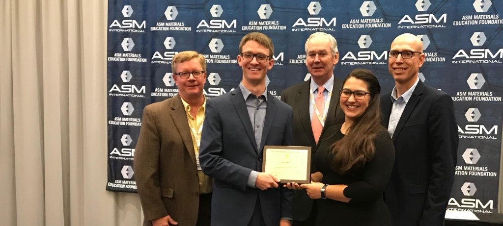 Celebrating the beginning of a winning streak: the 2019 student design team. From left, advisor Dr. Walt Milligan; student Kyle Hrubecky; William Mahoney, Chief Executive Officer of ASM International; student Erin VanDusen; and advisor Paul Sanders. Not pictured: students Lucas Itchue and Jacob Thompson. (Image courtesy ASM and Michigan Tech MSE) Three industry experts in materials science and engineering flank two students from an award-winning Michigan Tech team on the ASM International Awards Stage in 2019.