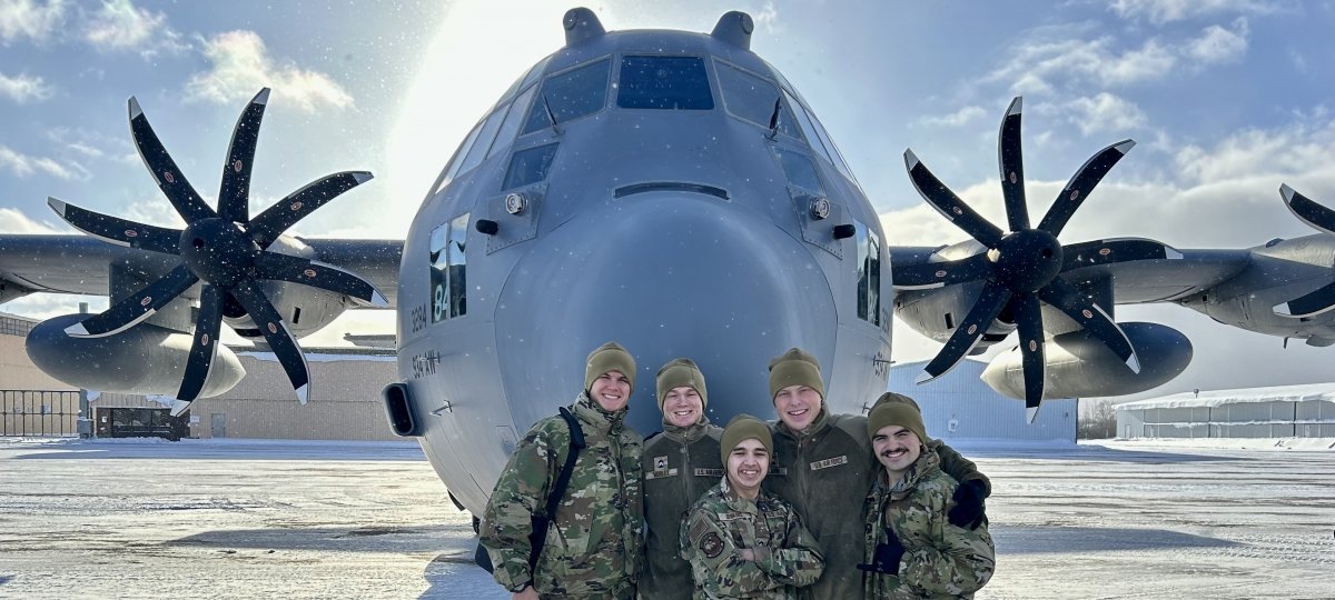 Among Huskies taking part in the experience were second-year cadets, from left, Cooper Marcukaitis, a finance major; Christopher Morley, a mechanical engineering major; Jorge Jenkins, a computer network and systems administration major; and Ethan Brink and Travis Crigger, both mechanical engineering majors. (Image courtesy Cooper Marcukaitis) Five Air Force ROTC cadets pose in front of the nose of a C-130 airplane.