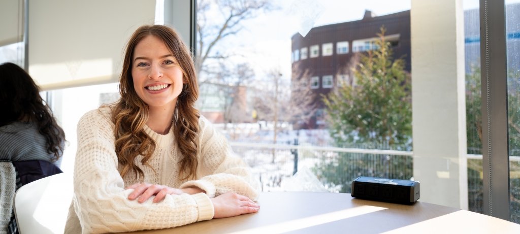 Hunter Malinowski, shown here in Van Pelt and Opie Library with the College of Computing's Rekhi Hall in the background, found the right mix of planning and spontaneity to get the most out of her Michigan Tech experience. A computer science and psychology student smiles from her table in the Library with Michigan Tech's College of Computing in the background.