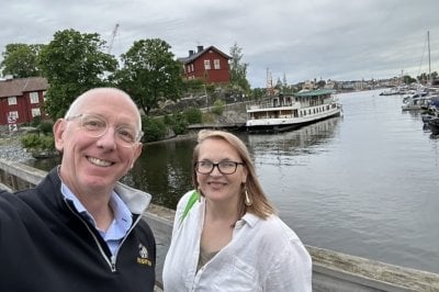 David Flaspohler and Tara Bal in front of a dock area with boats.