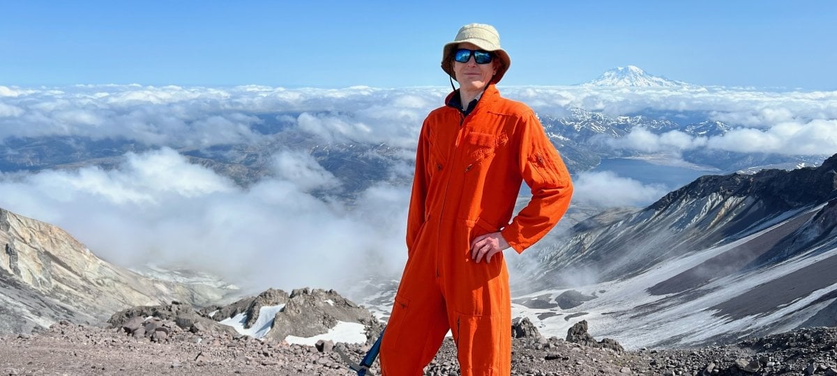 Simon Carn in an orange suit on top of a mountain.