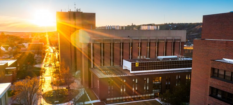 Central campus plaza and buildings with sunset in background.