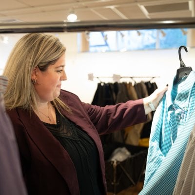 Alexandra Marshall looking at a dress shirt on a hangar.