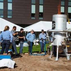 People standing around a forge set up outside on campus.