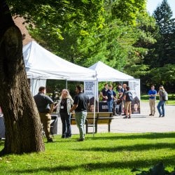 Students talking to recruiters beneath two white tents set up on campus.