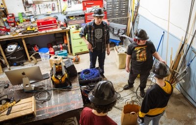 Students wearing hard hats working in a shop.