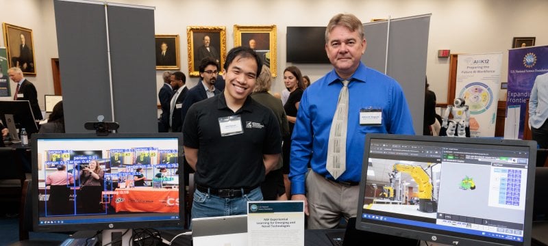 Vinh Nguyen and Alex Sergeyev standing behind their display table.