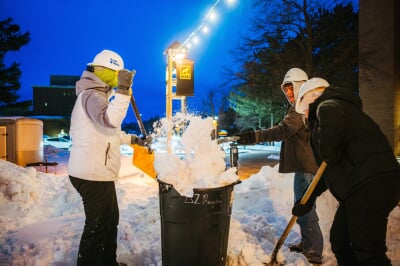 Students shovel snow into a tub during the all-nighter at Michigan Tech's Winter Carnival