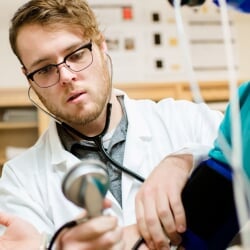 Student checking the pulse of another student with a stethoscope