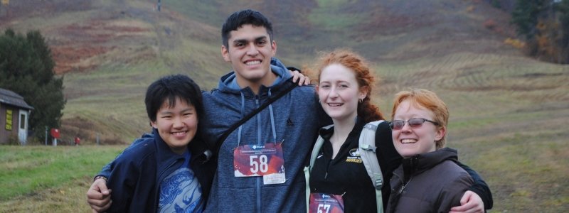 Four students standing in front of some landscape