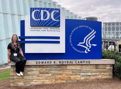 Marlee sitting on a wall around the CDC sign at the Edawrd R. Roybal Campus.