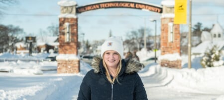 Skyler Spitzley standing outside in the winter with the gateway arch in the background.