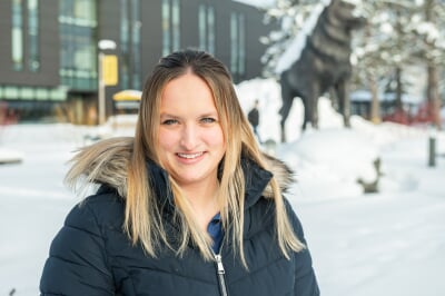 Skyler Spitzley standing outside in the winter with the Husky Statue in the background.