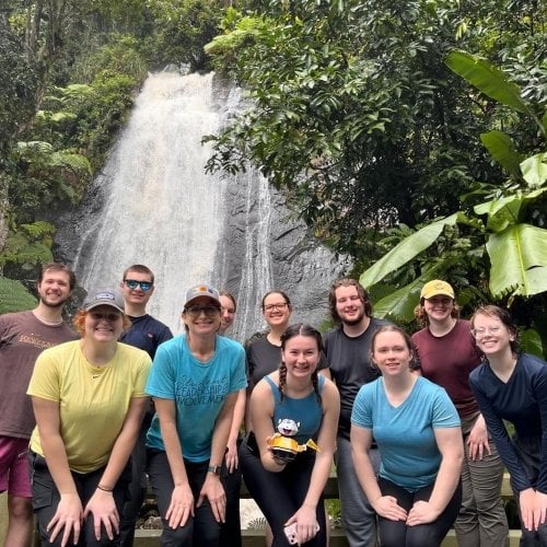 group poses in front of waterfall