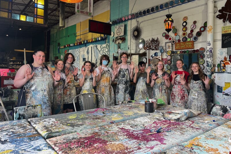 group posed with their hands up after painting