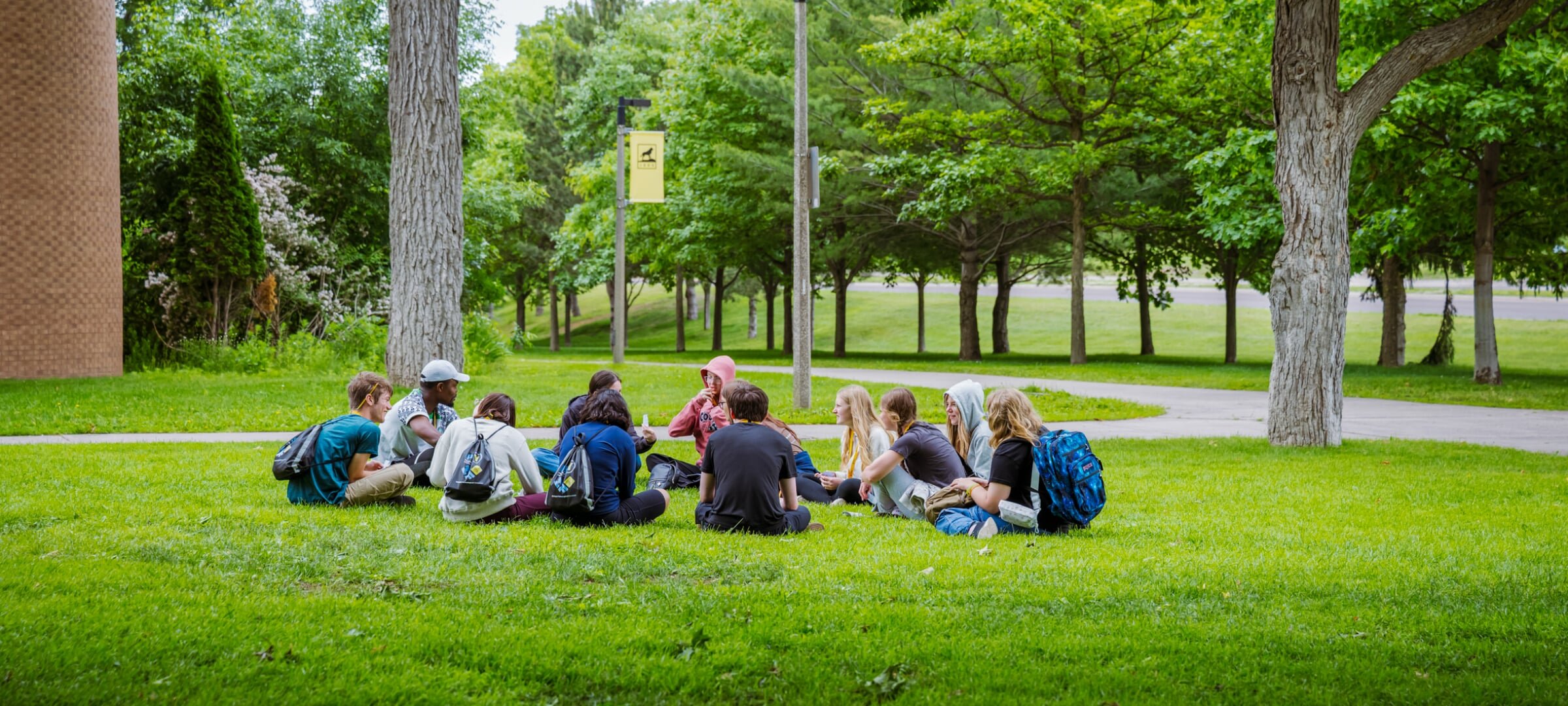 Group of students sitting in a circle on the grass.