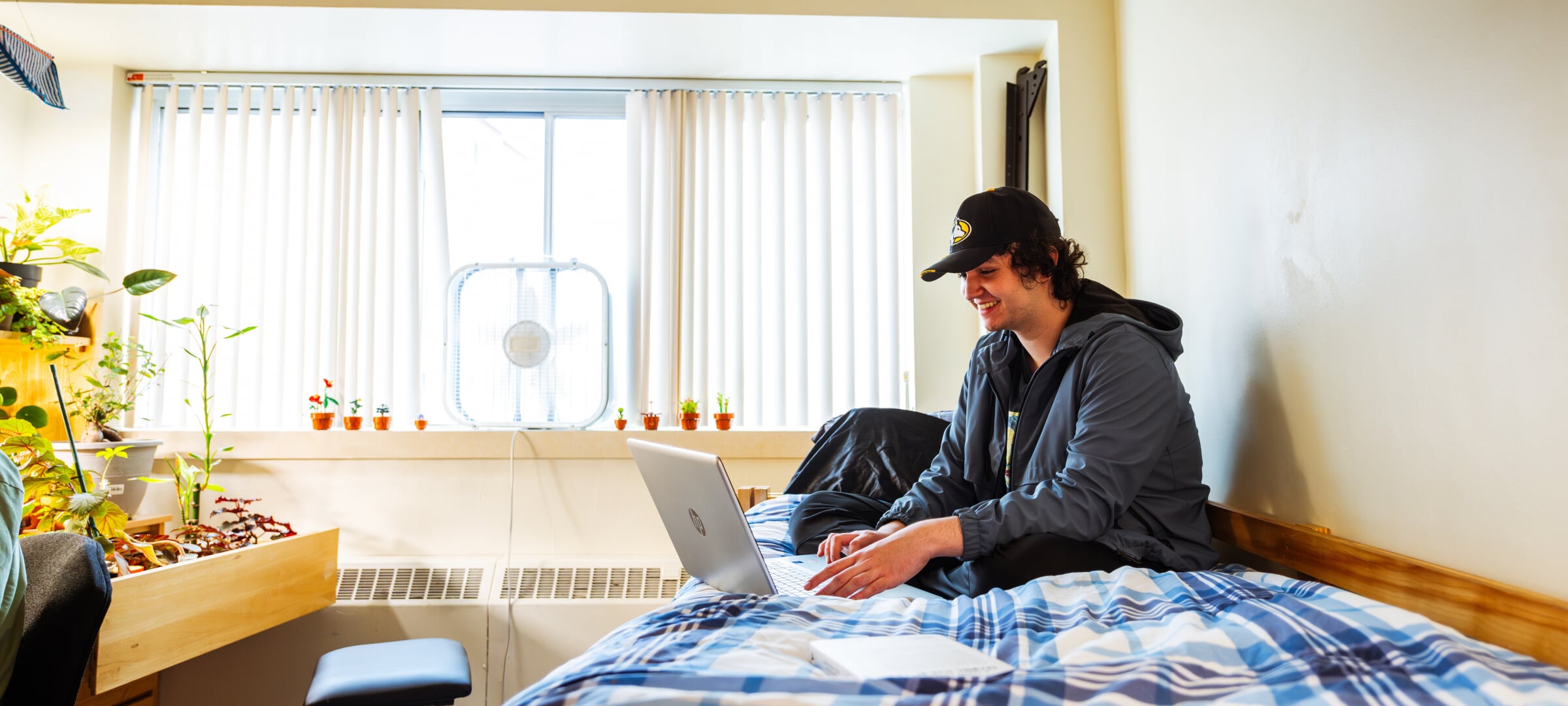 Student sitting on dorm room bed with laptop