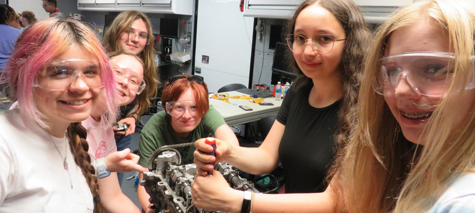 group of young women take apart an engine in WIAE