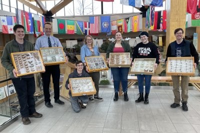 Seven people in the Forestry Atrium each holding a specimen case.