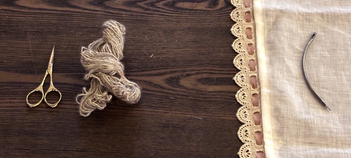 Lisa Gordillo, Stitching table from the installation "Magdalena: grief, hope, and witness" (2025) An oak table top, with scissors, human hair, and soft fabric