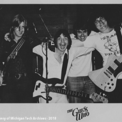Four long-haired male musicians with guitars on a poster that says Guess Who.